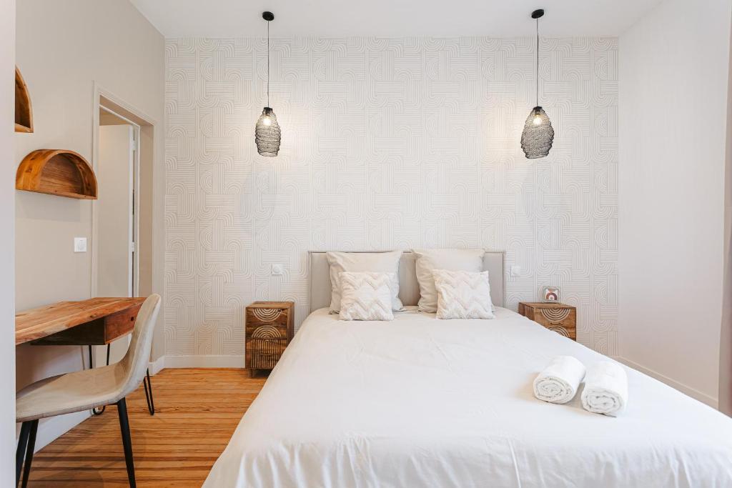 Un dormitorio con una gran cama blanca con dos almohadas. en Cosy appart proche du marché, en La Rochelle