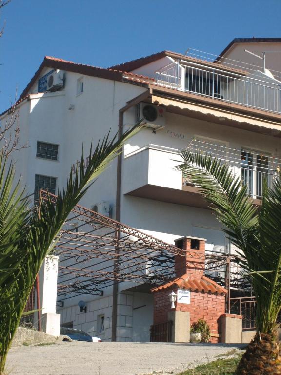a white building with a palm tree in front of it at Apartments Peričić in Podstrana