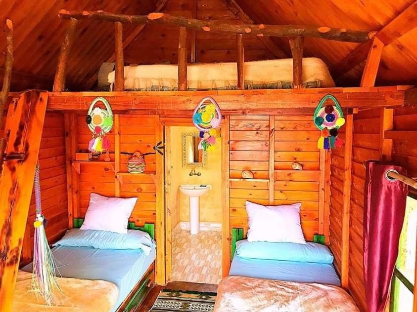 a bedroom with two beds in a log cabin at Marassina camp in Siwa
