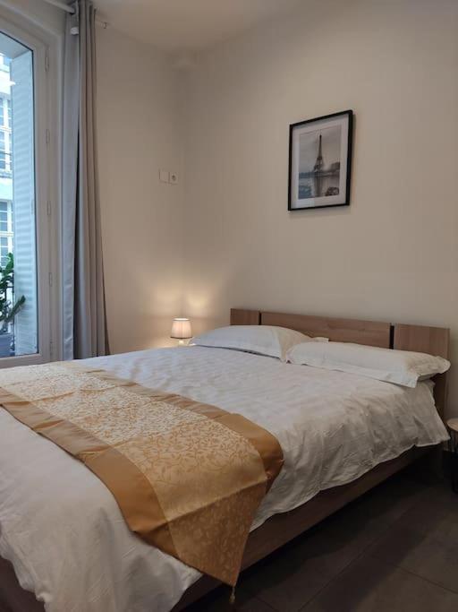 une chambre avec un grand lit avec un tableau sur le mur dans l'établissement Chez nous et Chez vous STUDIO, à Paris