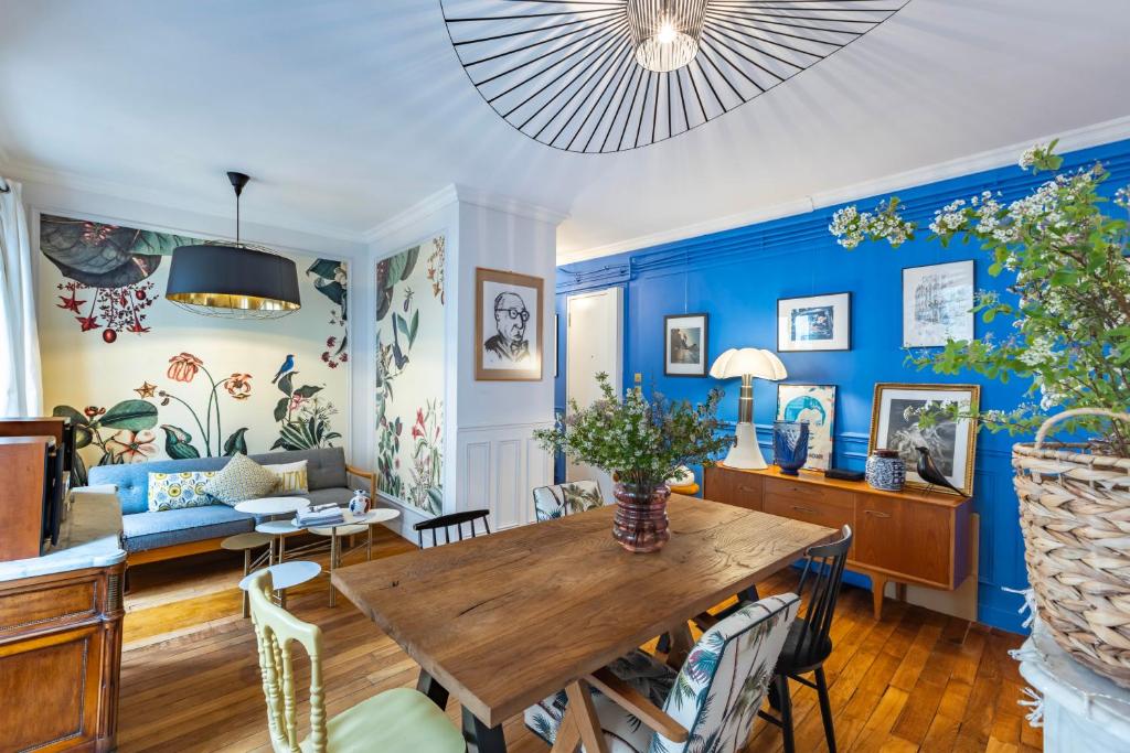d'un salon avec des murs bleus et une table en bois. dans l'établissement Appartement Unique - Art et Charme Paris 17ème, à Paris