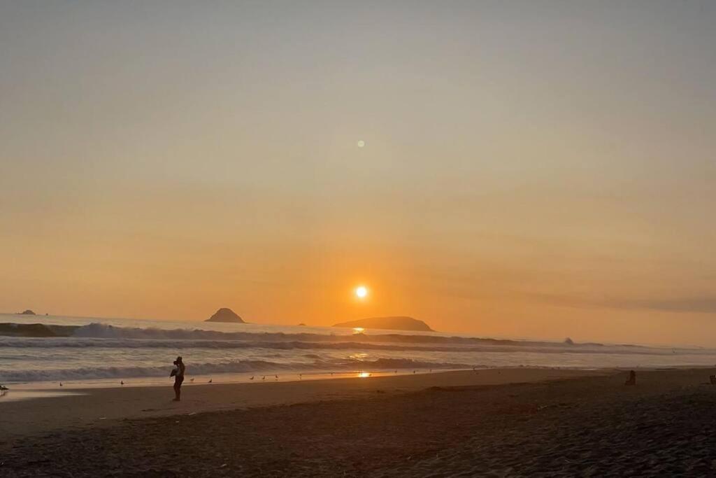 une personne debout sur la plage au coucher du soleil dans l'établissement Arica Home, à Lurín