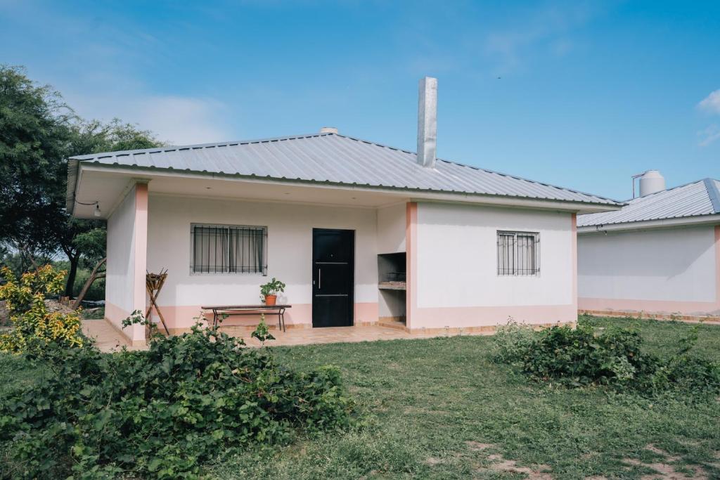 Biały dom z czarnymi drzwiami i ogródkiem w obiekcie Las Moras Del Manantial w mieście Termas de Río Hondo