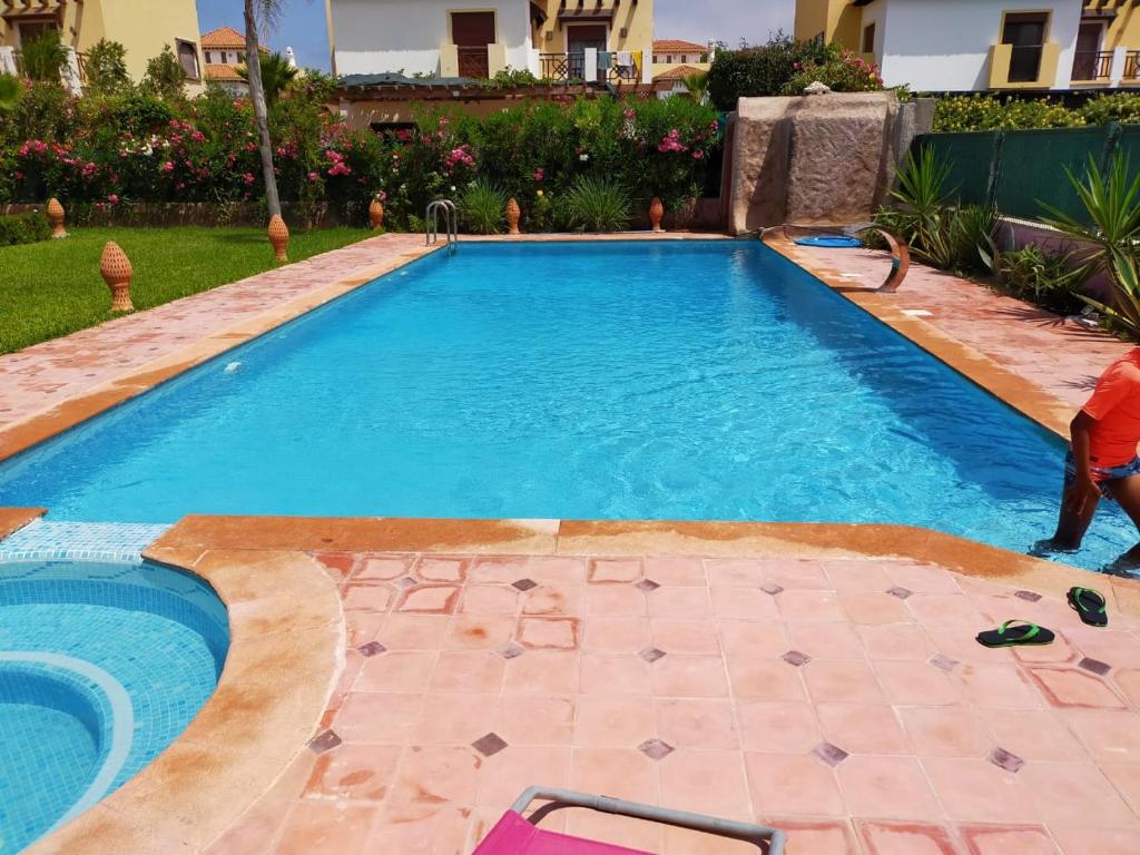a swimming pool in a yard with a person standing next to it at Marinazur in Saidia 