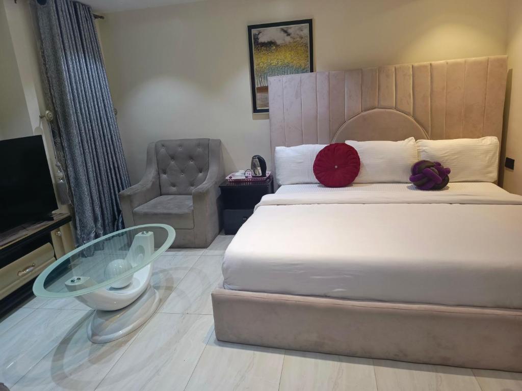 a bedroom with a bed and a chair and a television at Ikad Hotel and Suite in Lagos
