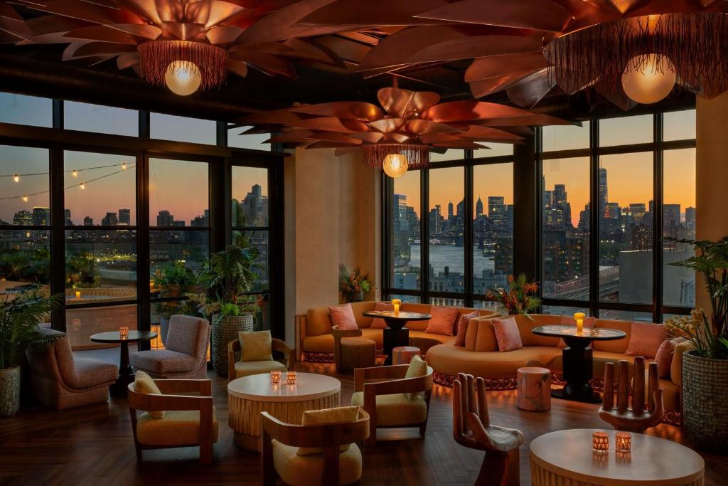 um restaurante com mesas e cadeiras e vista para a cidade em Moxy Brooklyn Williamsburg em Brooklyn