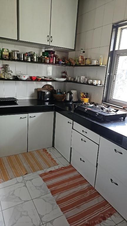 a kitchen with white cabinets and a black counter top at Laxmi Happy Home in Pune in Pune