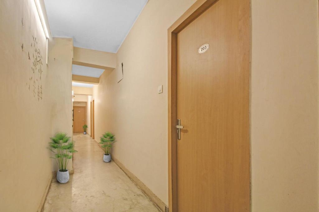 un couloir de bureau avec une porte et deux usines dans l'établissement OYO The Jumbo Stay, à Ālīpur