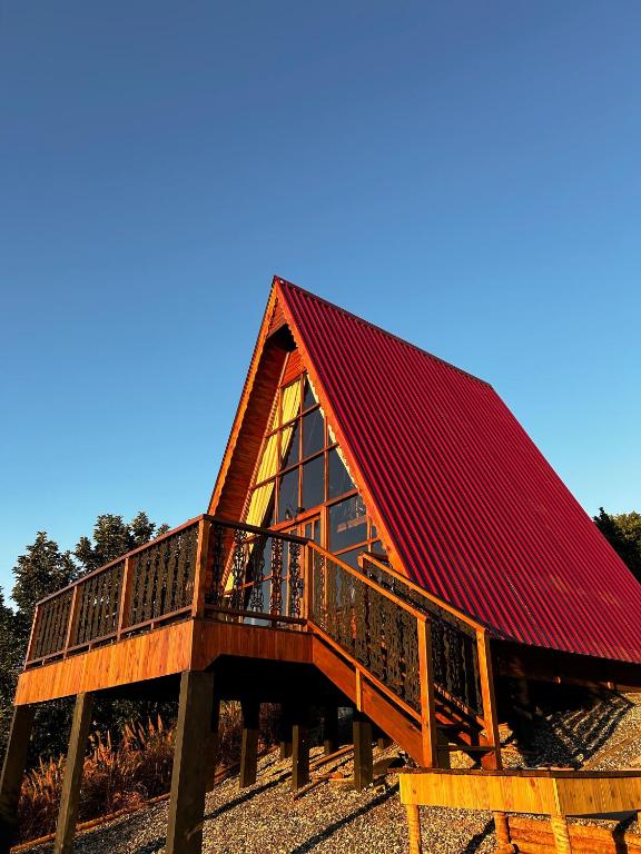 une grande cabine au toit rouge avec une terrasse dans l'établissement Refúgio Suiço em Vargem Alta, à Vargem Alta
