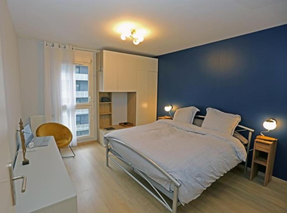 une chambre avec un grand lit avec un mur bleu dans l'établissement Appartement 4 pcs, à Saint-Denis