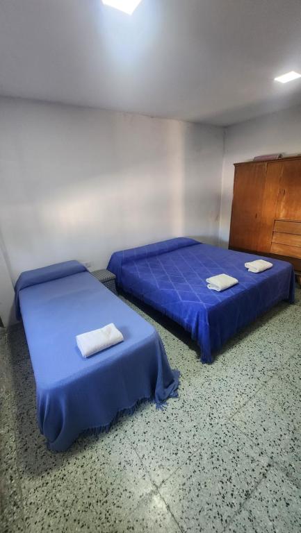 2 camas en una habitación con sábanas azules y toallas en Habitacion con baño en Termas de Río Hondo