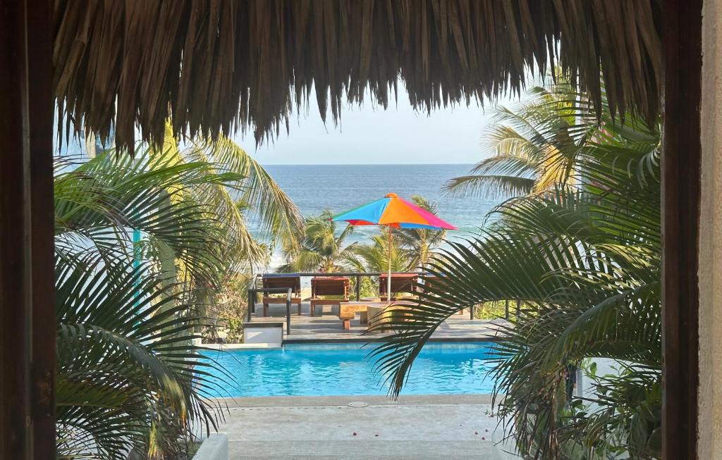 uma vista para uma piscina com um guarda-sol e para o oceano em Beachfront Paradise Boutique Hotel em Santa María Tonameca