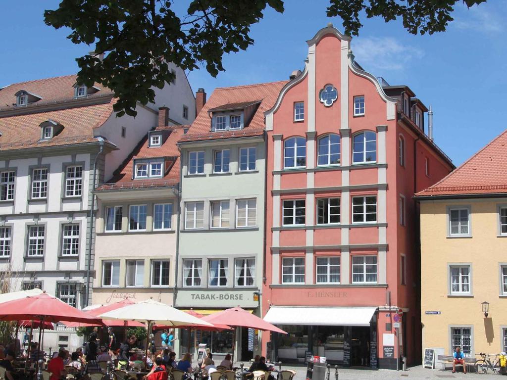 eine Gruppe von Gebäuden mit Tischen und Sonnenschirmen in der Unterkunft Ferienwohnungen Hensler in Lindau