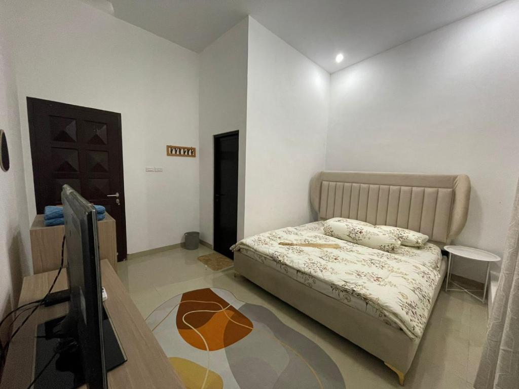 a bedroom with a bed and a flat screen tv at d’Viella Lampung in Kedaton