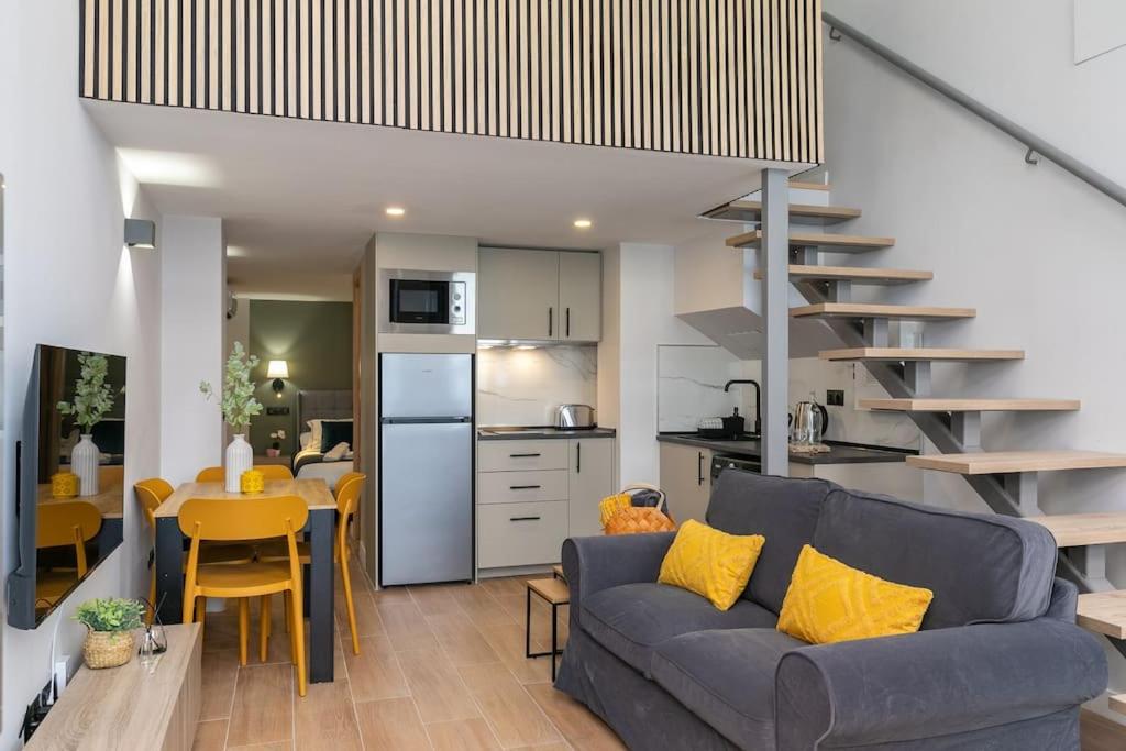 a living room with a blue couch and a kitchen at Nice new duplex in front of Palacio VistaAlegre in Madrid
