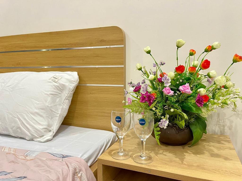una mesa con dos vasos y un jarrón con flores en Homestay Vinhomes Ocean Park S209, en Ða Tốn