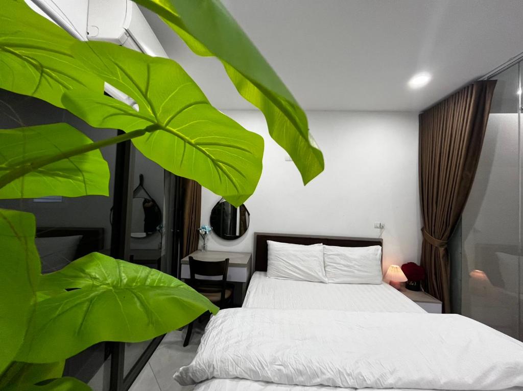ein Schlafzimmer mit einem Bett und einer großen grünen Pflanze in der Unterkunft Apartment 285 Đội Cấn, Hà Nội in Hanoi