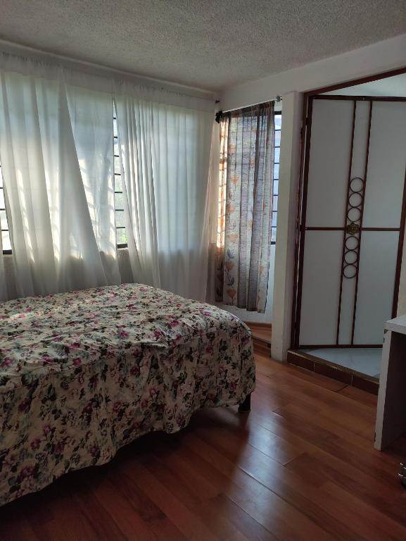 1 dormitorio con 1 cama con colcha de flores y ventanas en Habitaciones ampliación piloto, en Ciudad de México