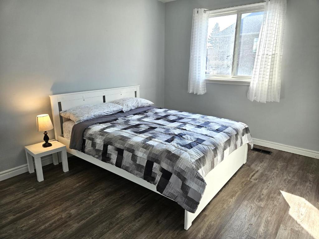 sypialnia z łóżkiem, lampką i oknem w obiekcie Modern Quiet Home By the Airport w mieście Mississauga