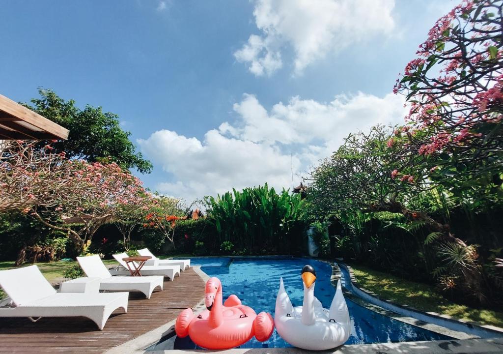 uma piscina com cisnes de borracha insufláveis num quintal em Harmony Beach Suite em Seminyak