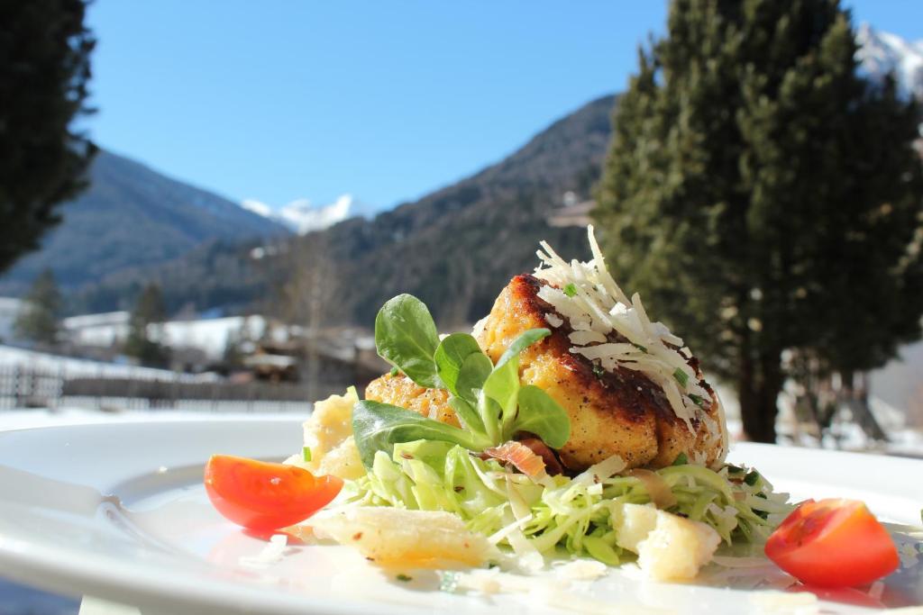 a plate of food with a salad on a table at Appartement Hotel Erlhof Deluxe in Lutago