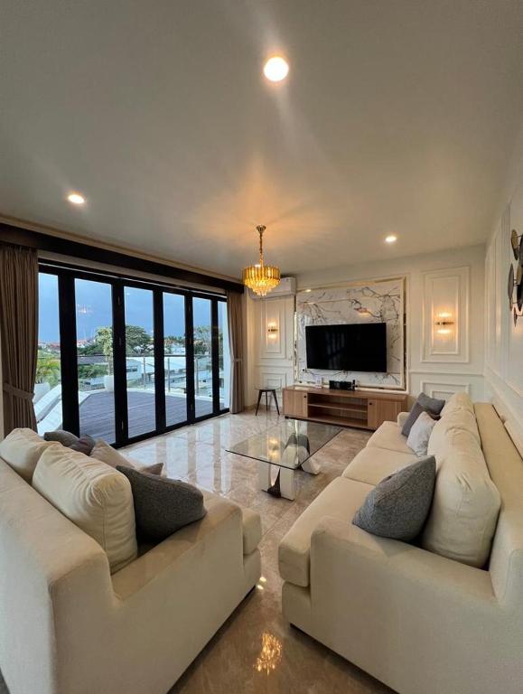 a living room with two white couches and a television at Penthouse Berawa - Canggu in Canggu