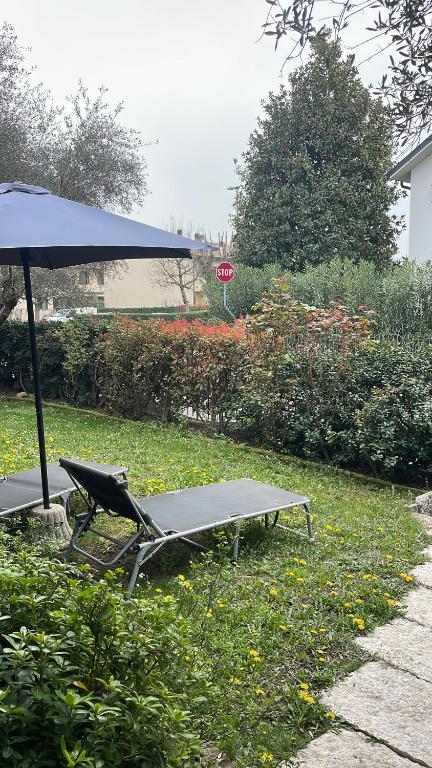 a picnic table and a chair under an umbrella at B&B Happy Days Affittacamere in Sirmione
