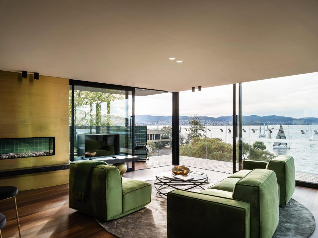 sala de estar con sillas verdes y chimenea en 'Sydney' - Luxurious waterfront penthouse in Battery Point, en Hobart