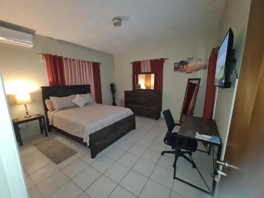 a bedroom with a bed and a desk and a television at Tropix Getaway - rental car available in Crocus Hill