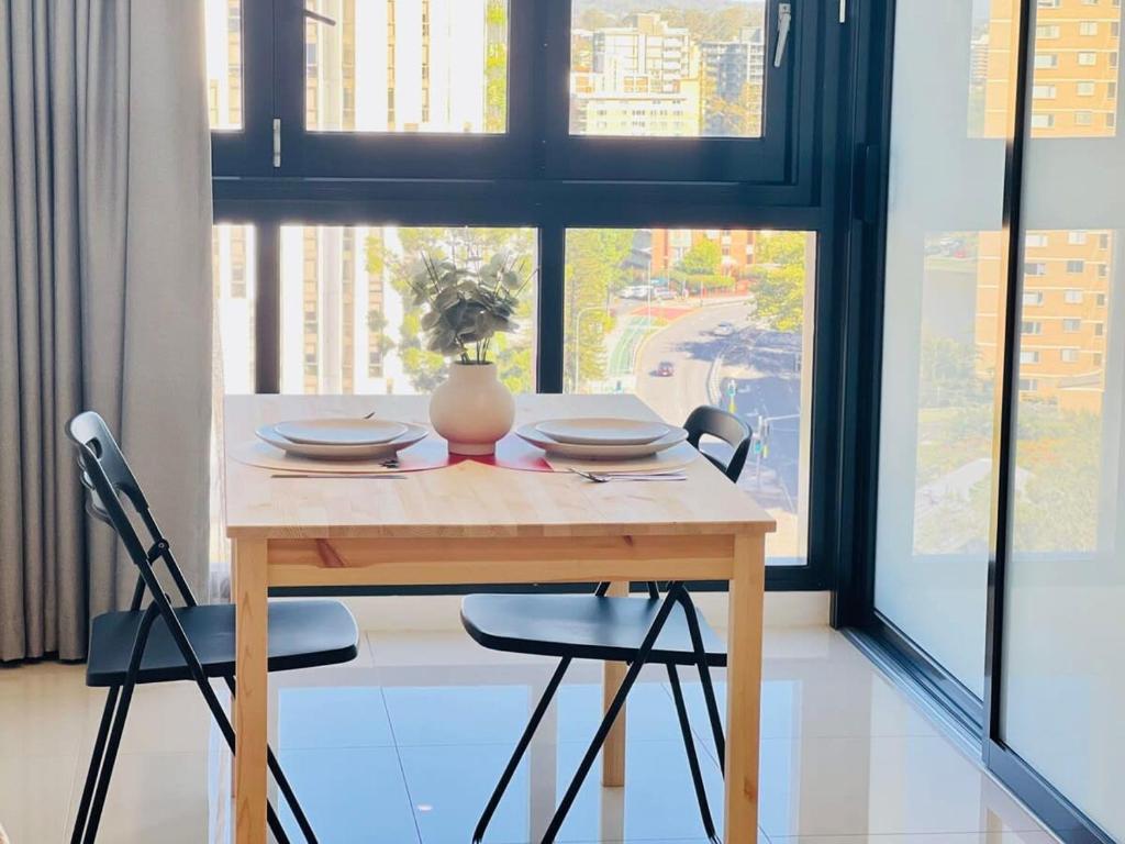 a table with two chairs and a vase on it at CASSA TOOWONG - Convenient 1B Apt at Central Location with Parking Managed by The Cassa in Brisbane