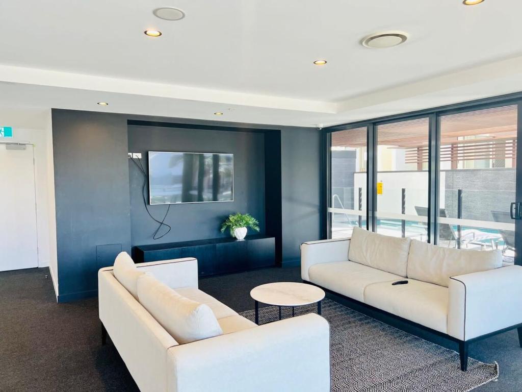 a living room with two white couches and a table at CASSA TOOWONG - Convenient 1B Apt at Central Location with Parking Managed by The Cassa in Brisbane