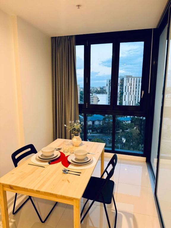 a dining room table with chairs and a large window at CASSA TOOWONG - Convenient 1B Apt at Central Location with Parking Managed by The Cassa in Brisbane