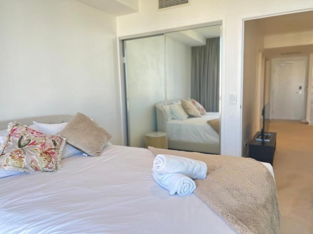 a white bed with two towels on top of it at CASSA TOOWONG - Convenient 1B Apt at Central Location with Parking Managed by The Cassa in Brisbane