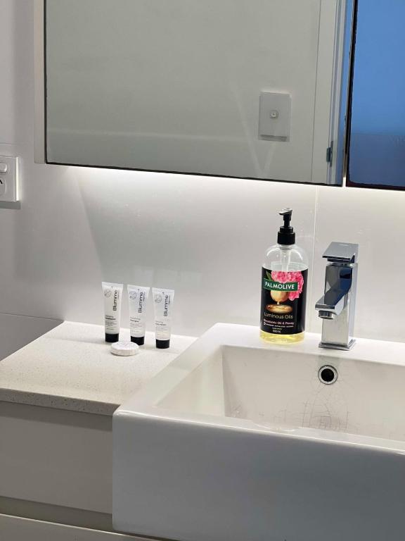 a bathroom sink with a bottle of soap and two glasses at CASSA TOOWONG - Convenient 1B Apt at Central Location with Parking Managed by The Cassa in Brisbane