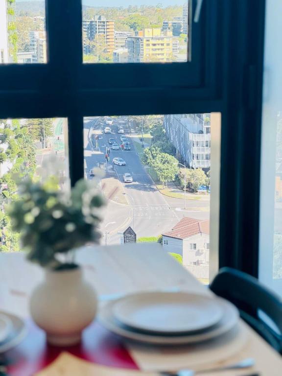 a table with plates and a vase of flowers on a window at CASSA TOOWONG - Convenient 1B Apt at Central Location with Parking Managed by The Cassa in Brisbane