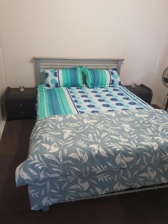 a bedroom with a bed with blue and white sheets and pillows at Comfort Home in Wyndham Vale