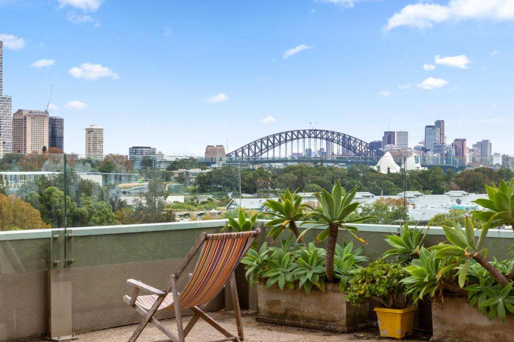 a chair on a balcony with a view of the sydney harbour at Chic Studio with Pool Overlooking the City in Sydney
