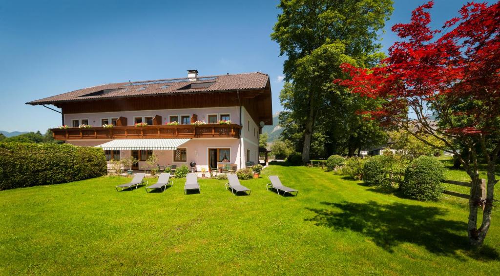 un groupe de chaises assises dans l'herbe devant une maison dans l'établissement Haus Wolfgangsee, à Sankt Gilgen