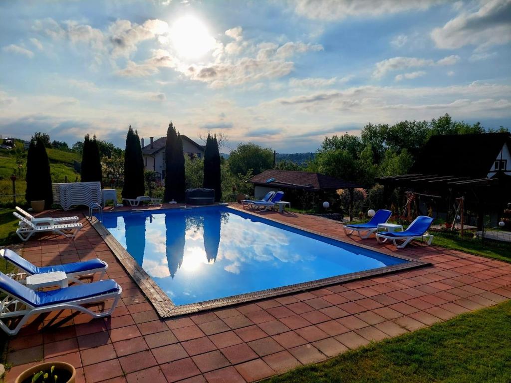 una piscina con sillas y el sol en el cielo en Balada dintre dealuri, Sibiu, Cisnadioara, en Cisnădioara