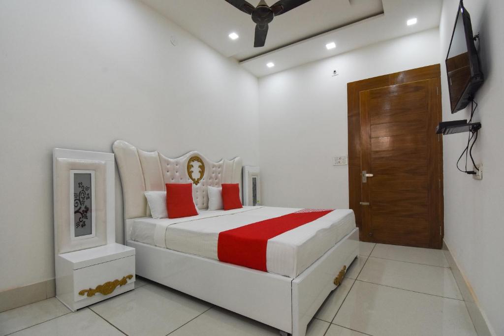 ein weißes Schlafzimmer mit einem großen Bett mit roten Kissen in der Unterkunft Hotel Shagun in Karnal