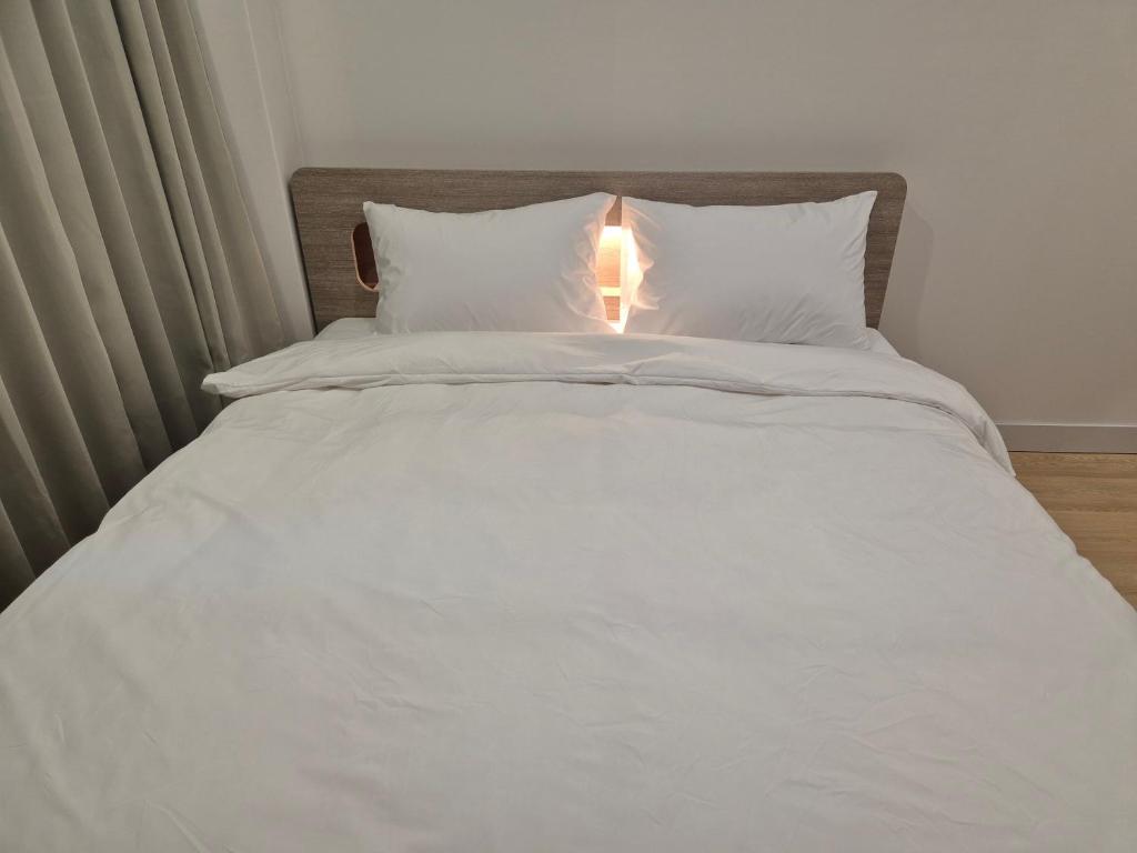 una cama blanca con una luz encima en Gwang Jang Hotel en Busan