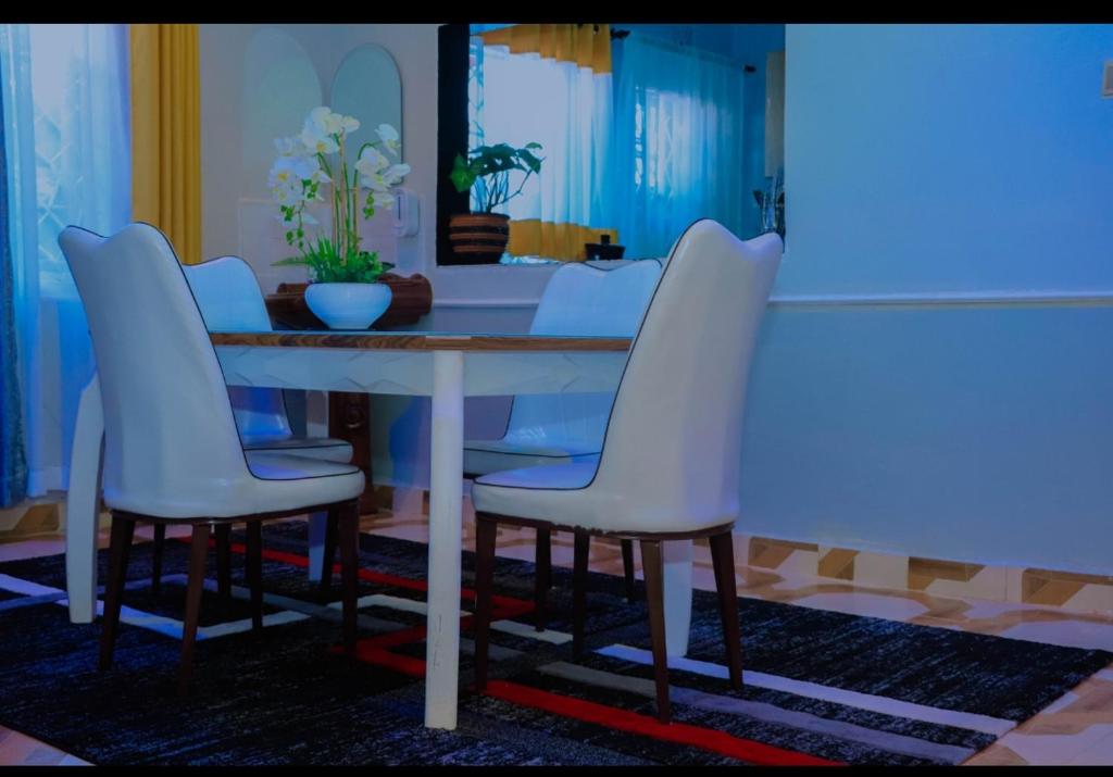 a dining room table with four white chairs around it at Greenstar home in Kisii