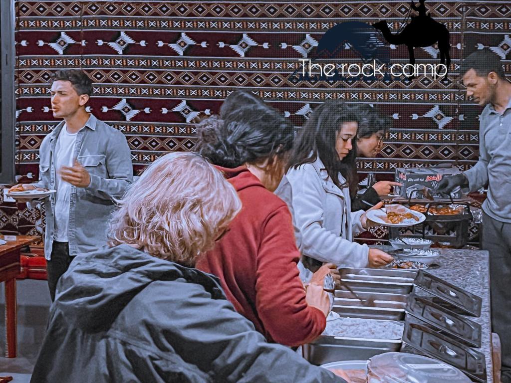 a group of people standing around a kitchen preparing food at The Rock Camp in Wadi Rum
