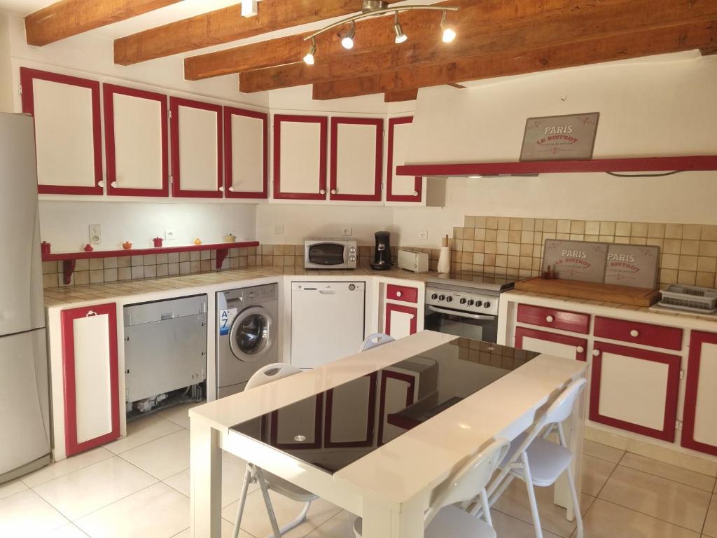 eine Küche mit roten Schränken und einem Tisch mit Stühlen in der Unterkunft Maison,Gite 8 places in Rivières
