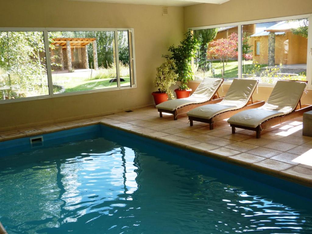 a swimming pool with chaise lounge chairs next to a swimming pool at Cabañas Monte Coiron in Malargüe