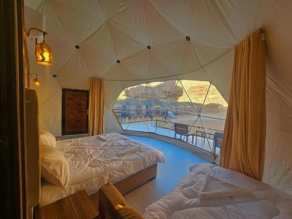 a bedroom with two beds and a large window at Star Camp Wadi Rum in Wadi Rum