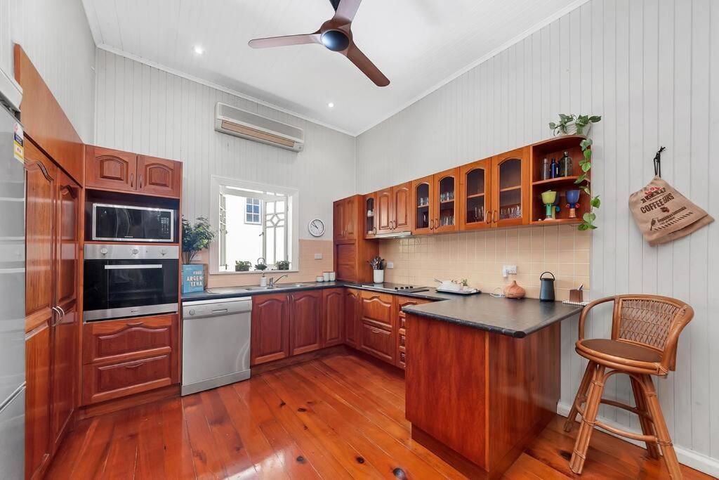a large kitchen with wooden cabinets and a ceiling fan at Masterfully Restored Queenslander Near Esplanade in Cairns North