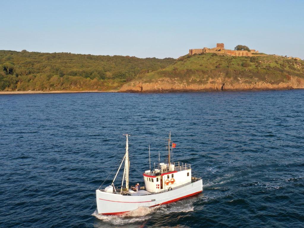 a boat in the water with a castle in the background at Unique Boat Accomodation - Bornholm - Fjælstavn in Hasle