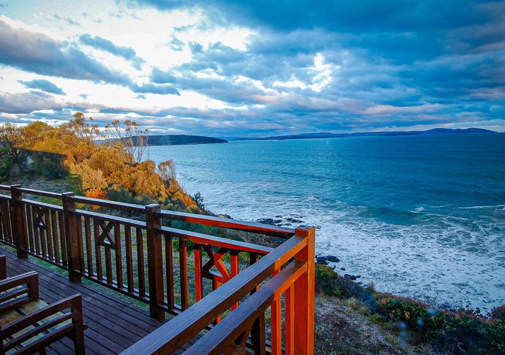 a wooden deck with a view of the ocean at Waterfront - Bluff Beach House, Park Beach in Dodges Ferry
