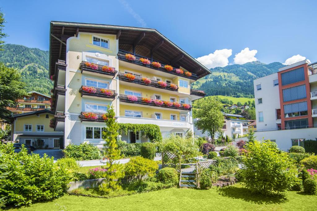 a hotel with a garden and mountains in the background at Haus Mühlbacher - inklusive kostenfreiem Eintritt in die Alpentherme in Bad Hofgastein